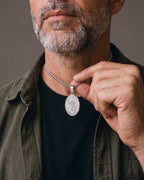 Hand lifting the Atlas Saint Michael Pendant Necklace at the collarbone