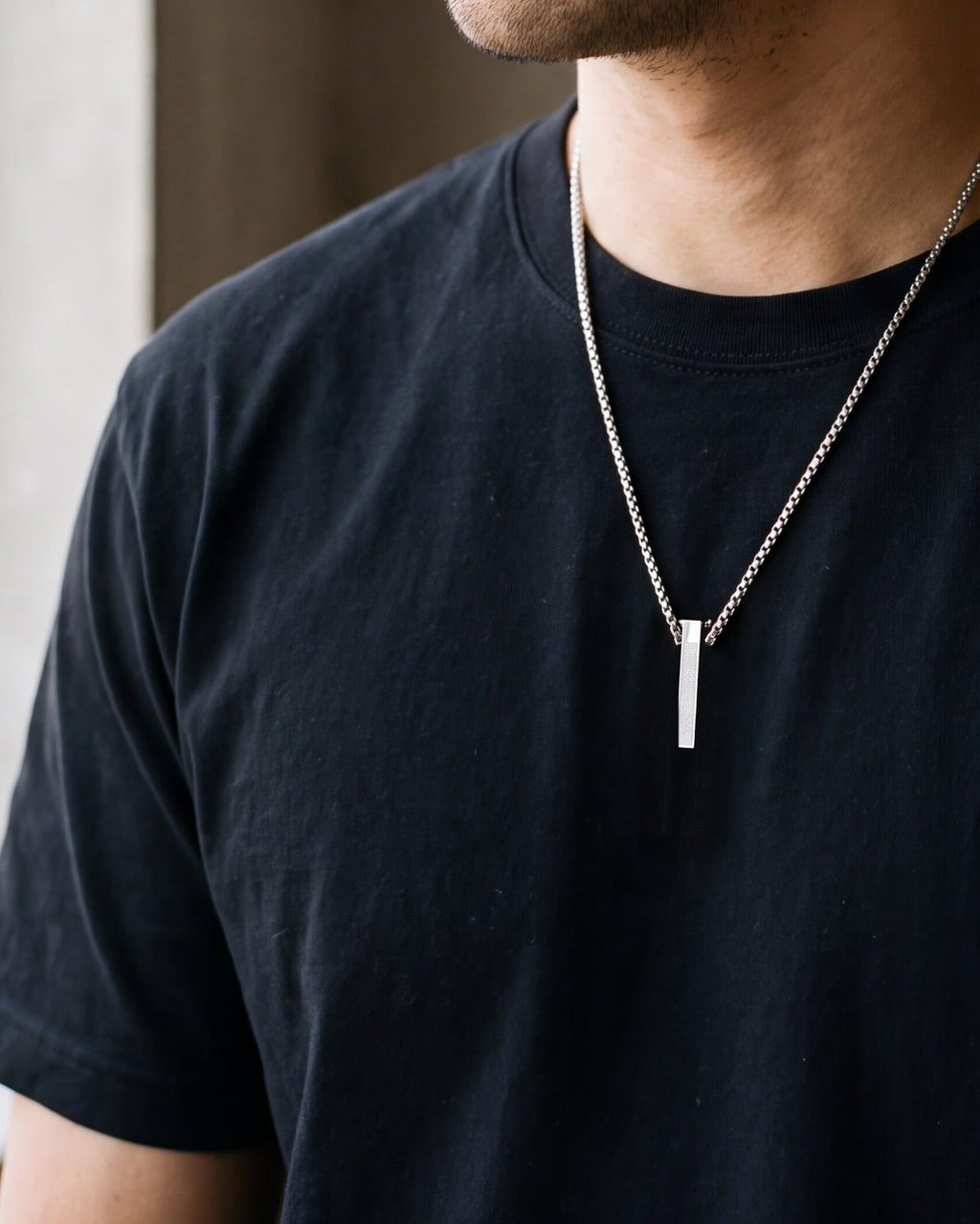 Close-up of the silver-tone Atlas script-etched bar pendant necklace worn, true size