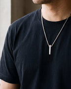 Close-up of the silver-tone Atlas script-etched bar pendant necklace worn, true size