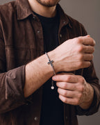Hand adjusting the Atlas Sideways Cross Bracelet in Stainless Steel on the wrist