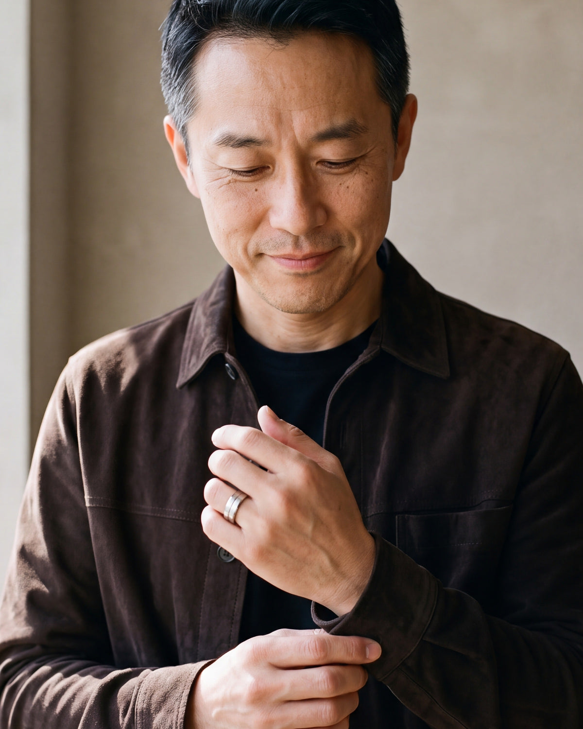 Man in a brown suede overshirt adjusting his cuff, wearing the silver Atlas single groove band ring