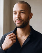 Man in a black shirt with his hand at the collar, wearing the 3 mm gold-tone Atlas Cuban chain