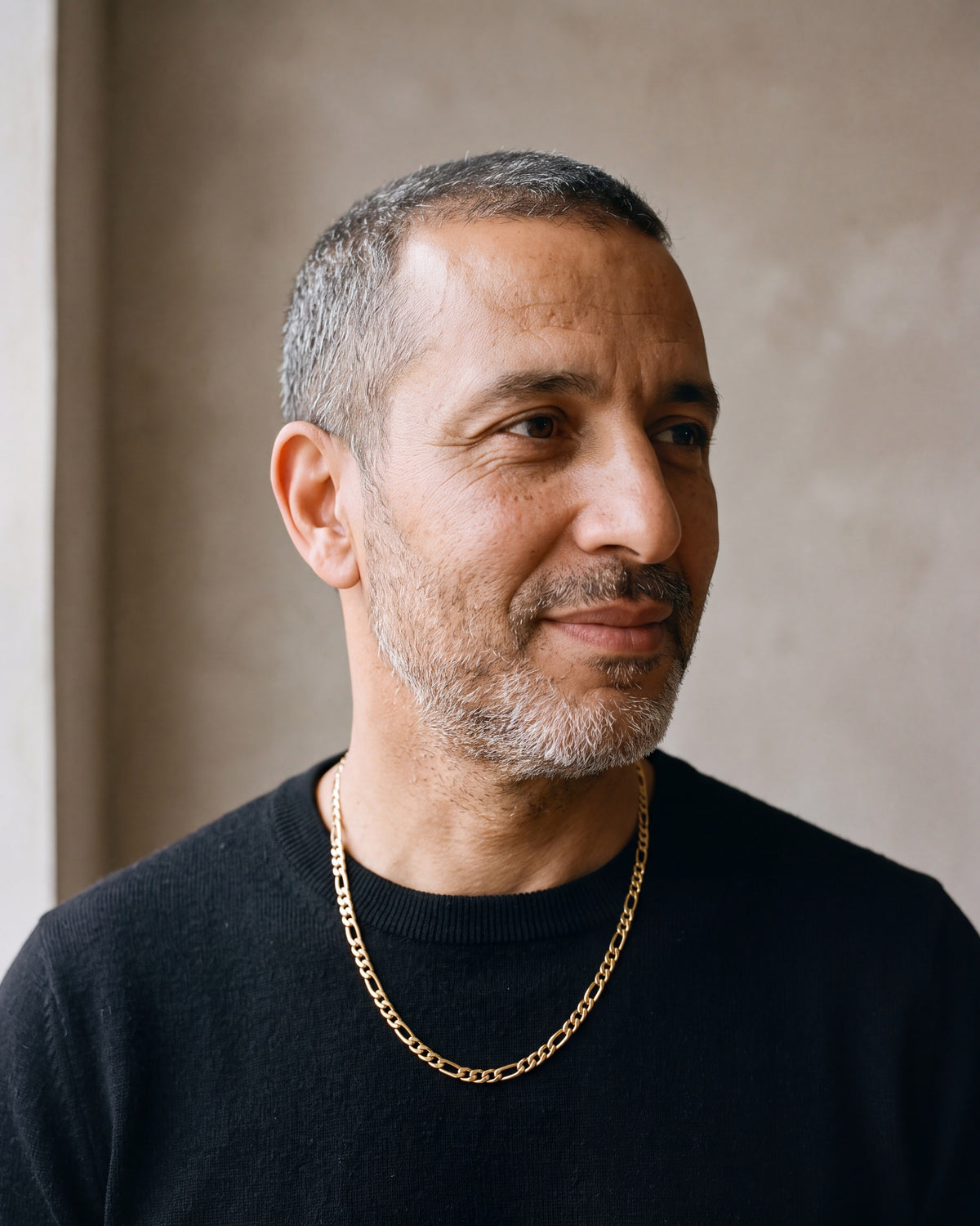 Man in a black merino sweater wearing the Atlas slim Figaro chain in gold-tone steel