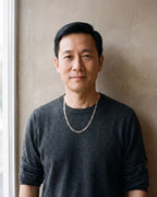 Man in a charcoal knit sweater by a window wearing the Atlas slim Figaro chain in silver-tone steel