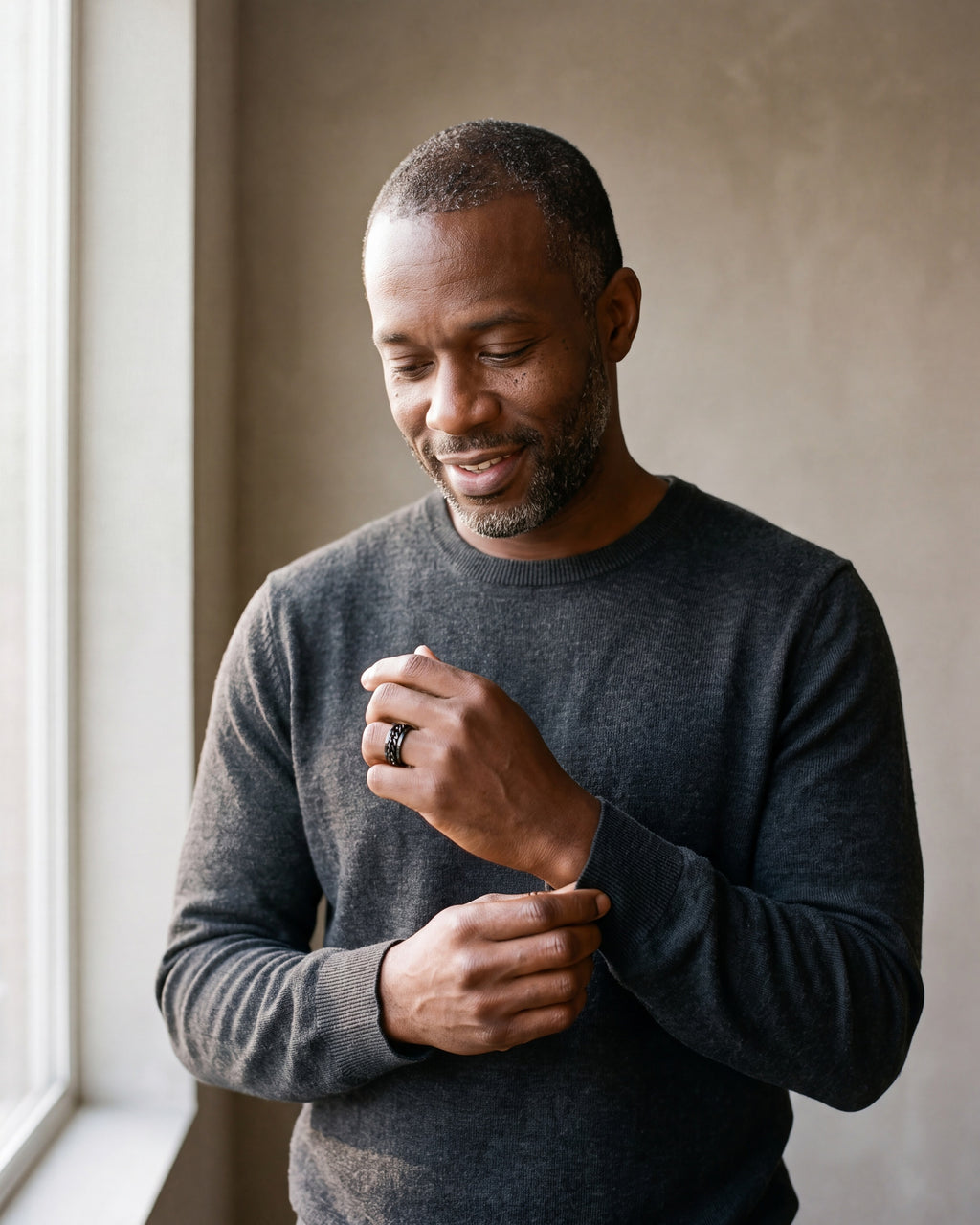 Man in a charcoal sweater adjusting his sleeve wearing the black Atlas spinner chain ring