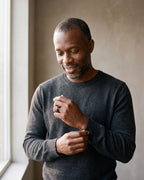 Man in a charcoal sweater adjusting his sleeve wearing the black Atlas spinner chain ring