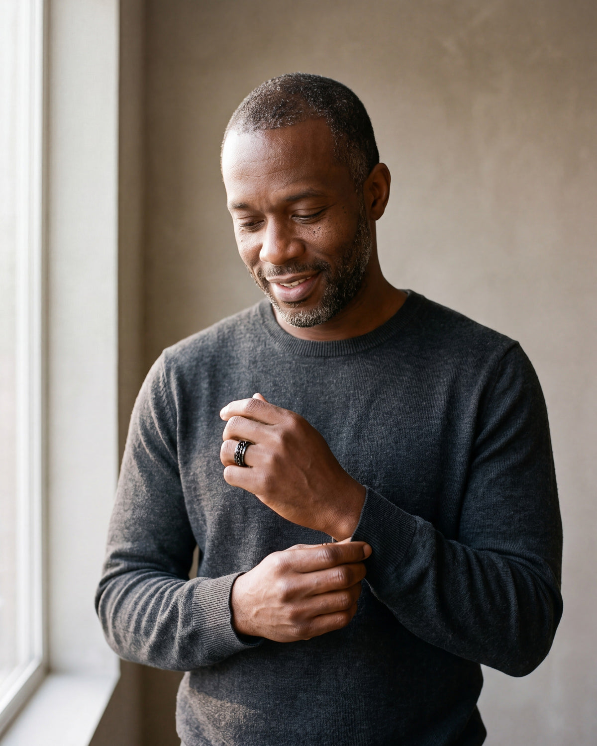 Man in a charcoal sweater adjusting his sleeve wearing the black Atlas spinner chain ring