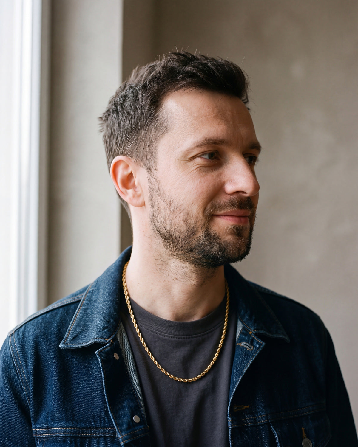 Man in a denim jacket over a charcoal T-shirt wearing the gold-tone Atlas spiral rope chain