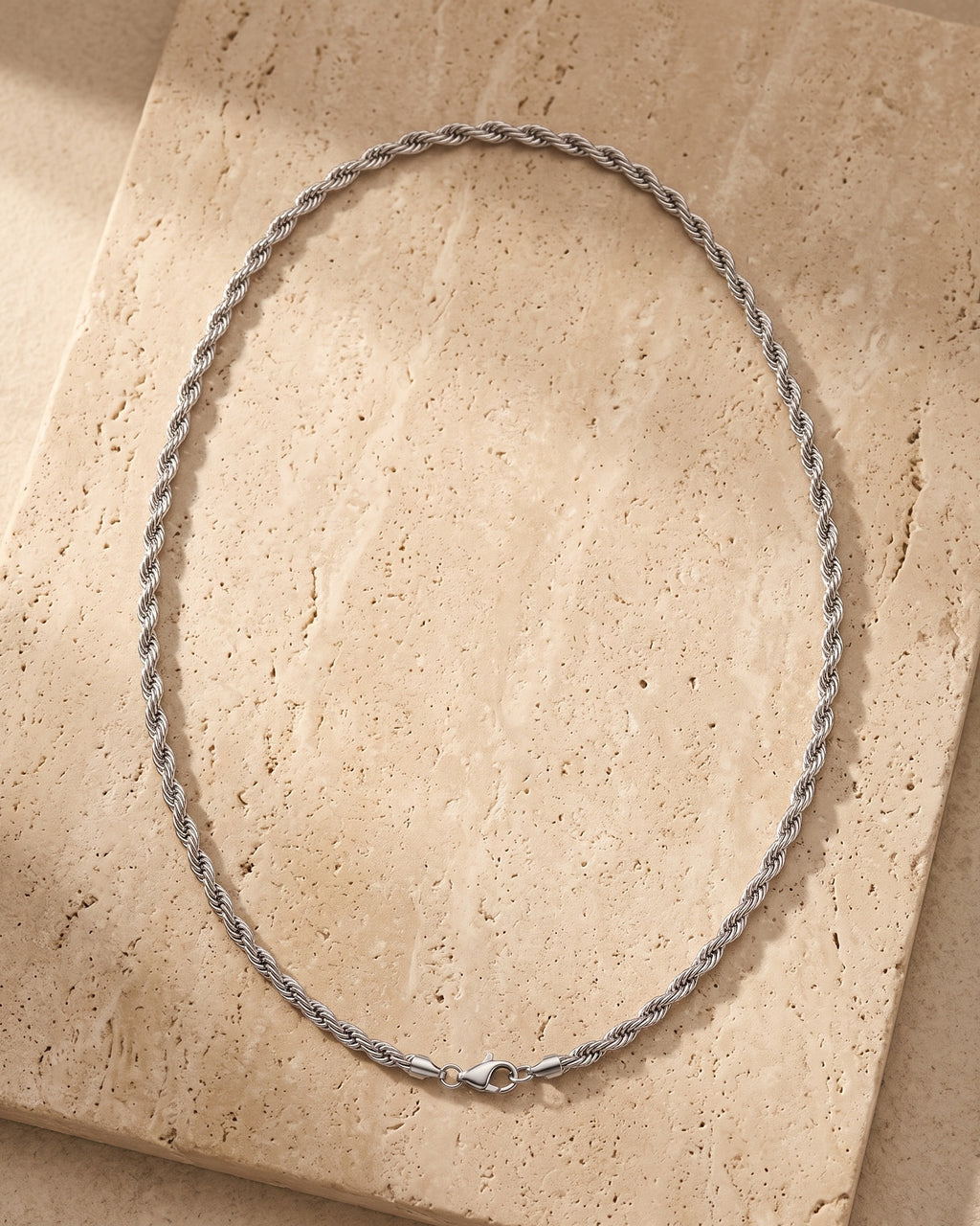 The whole silver-tone Atlas Twisted Rope Chain lying on warm travertine stone