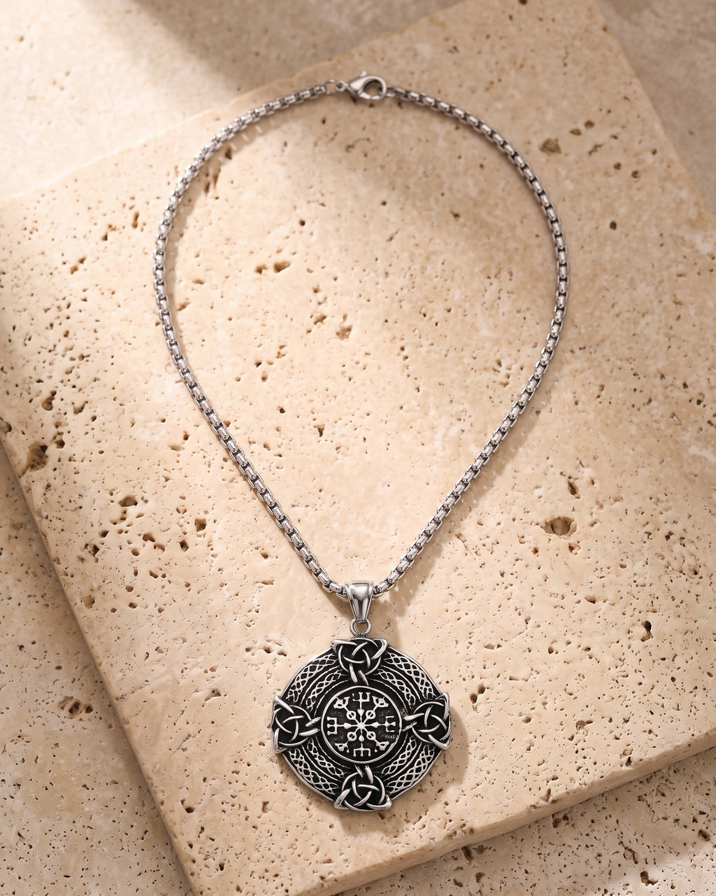 The whole silver-tone Atlas Vegvisir Viking Compass Pendant Necklace lying on warm travertine stone