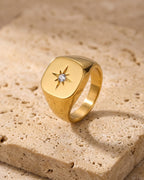 Atlas gold-tone star signet ring standing on warm stone