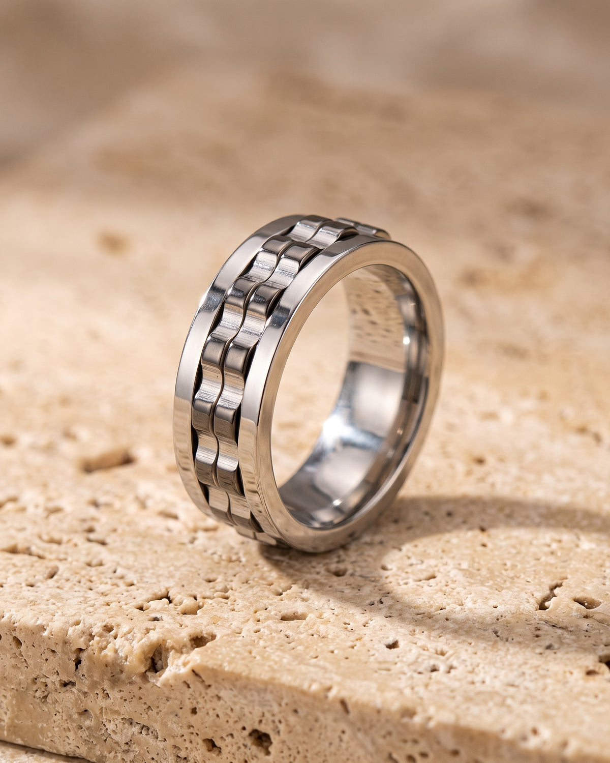 The whole silver-tone Atlas textured spinner ring laid on warm stone