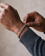 Hand adjusting the Atlas Titanium Steel Cuban Link Bracelet on the wrist
