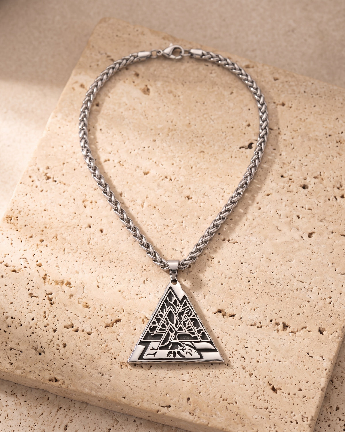 The whole Atlas Valknut triangle pendant necklace on warm stone, tree of life detail