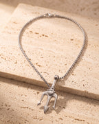 The whole silver-tone Atlas trident pendant necklace on warm stone