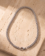 The whole silver-tone Atlas wheat chain laid on warm stone, lobster clasp closed