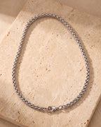 Entire Atlas wheat chain in silver-tone steel, lying flat on warm stone