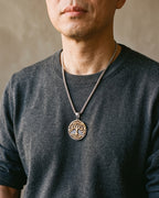 Atlas Tree of Life medallion pendant with gold-tone tree worn on the chest, close-up