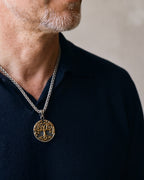 Close-up of the Atlas tree of life pendant worn on a navy knit polo