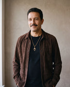 Man in a brown suede overshirt wearing the gold-tone Atlas trident pendant necklace