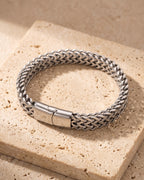 The whole silver-tone Atlas twin wheat chain bracelet lying on warm travertine stone