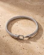 The silver Atlas twisted cable bangle on warm stone, horseshoe clasp
