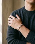 Atlas twisted cable bangle in silver-tone stainless steel worn on the wrist, close-up