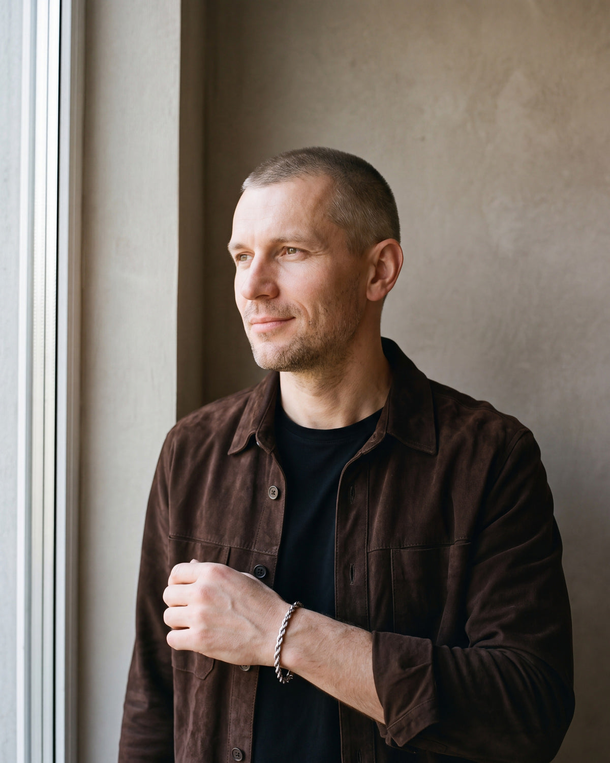 Man in a dark brown suede overshirt open over a black t-shirt wearing the silver-tone Atlas Twisted Rope Bracelet