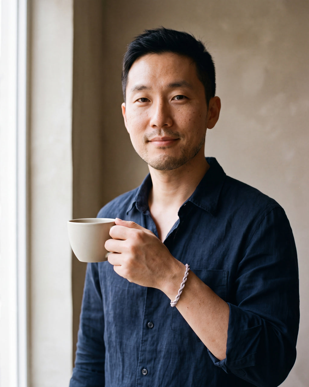 Man in a dark navy linen shirt by a window wearing the silver-tone Atlas Twisted Rope Bracelet