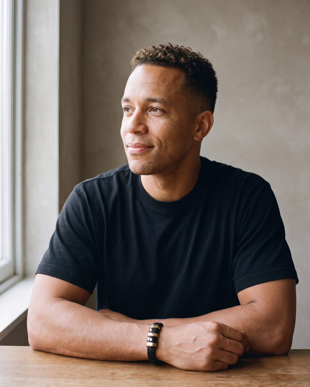 Second man in a plain heavyweight black cotton crew-neck t-shirt (thick wearing the gold-tone Atlas two-tone bar braided leather bracelet