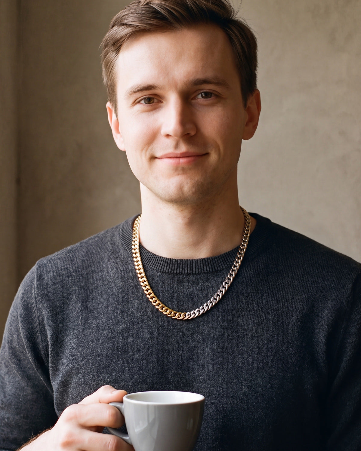 Man in a charcoal sweater holding a coffee cup, wearing the Atlas two-tone Cuban chain