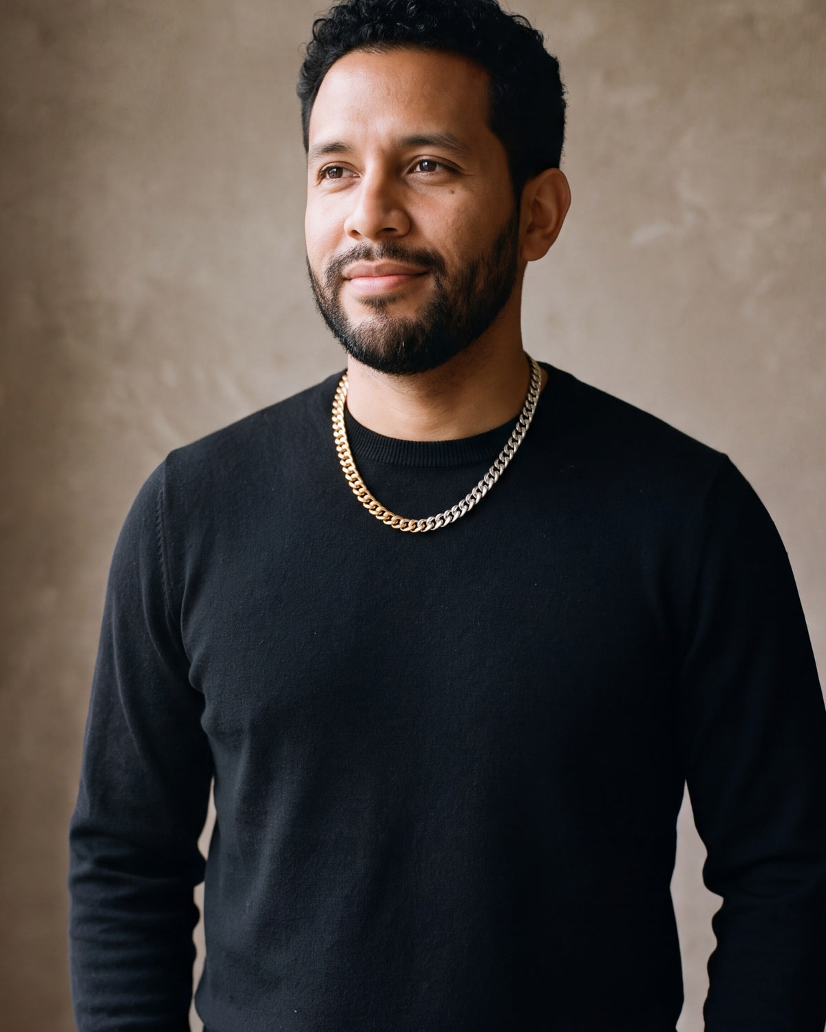 Man in a black sweater with his hands in his pockets, wearing the Atlas two-tone Cuban chain