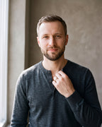 Man in a fine-gauge charcoal-grey merino knit with a henley neckline by a window wearing the plain Atlas two-tone frosted band
