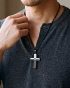 Close-up of the black and silver Atlas inlaid cross pendant worn on a henley