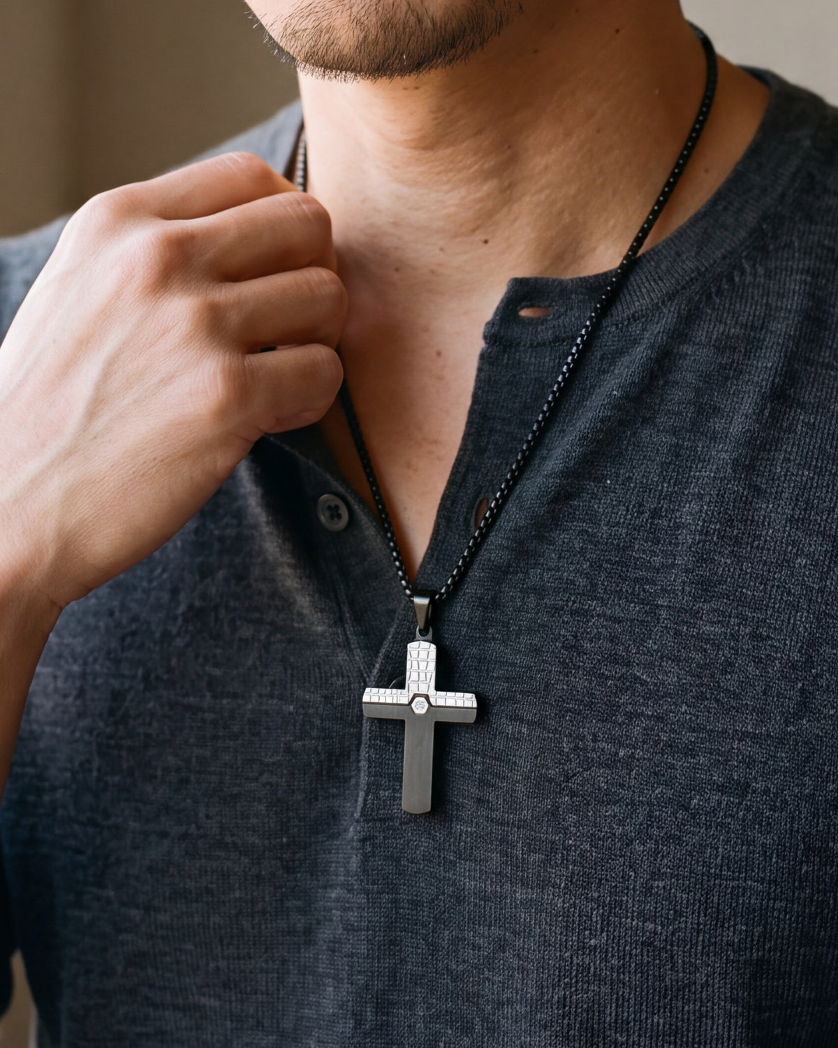Close-up of the black and silver Atlas inlaid cross pendant worn on a henley