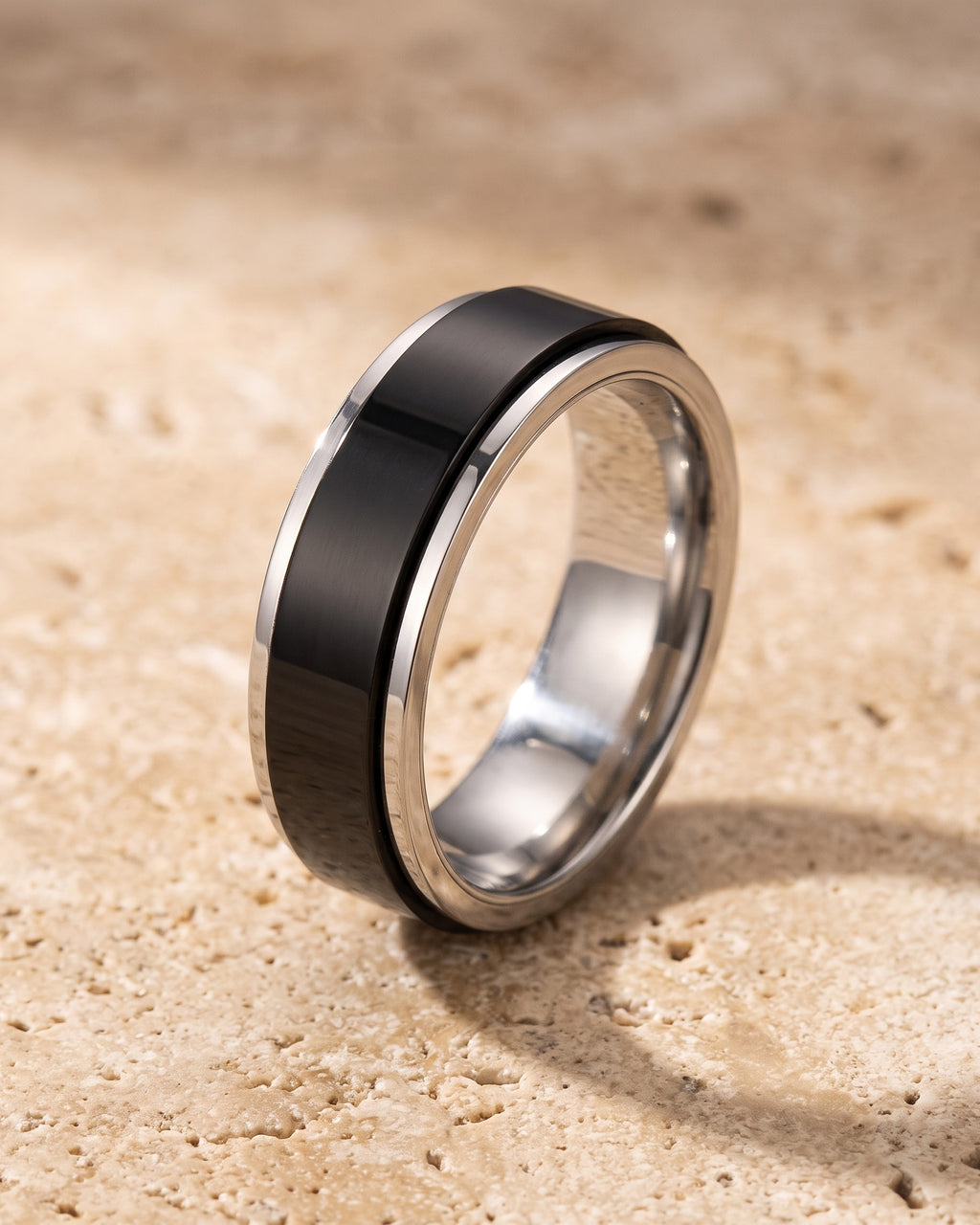 The whole silver-tone Atlas two-tone spinner ring lying on warm travertine stone