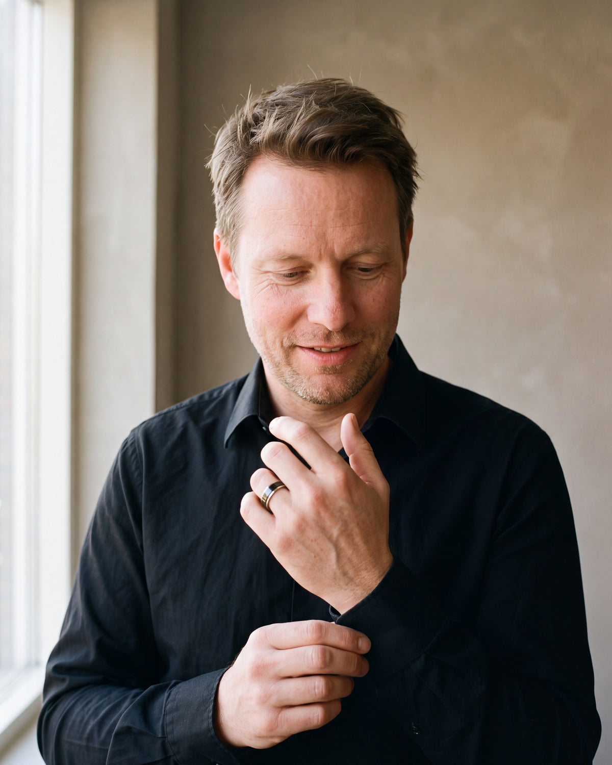 Man in a black fine cotton shirt by a window wearing the silver-tone Atlas two-tone spinner ring