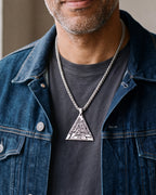 Close-up of the Atlas Valknut triangle pendant worn on a charcoal T-shirt