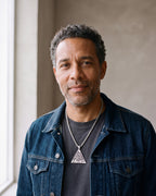 Man in a denim jacket wearing the silver Atlas Valknut triangle pendant on a wheat chain