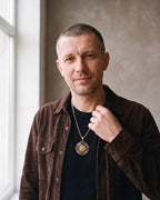 Man in a dark brown suede overshirt open over a black t-shirt wearing the gold-tone Atlas Vegvisir Viking Compass Pendant Necklace