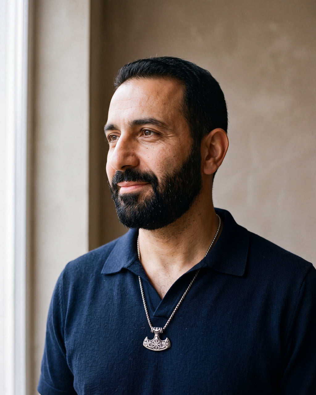 Second man in a navy fine-gauge knit polo with an open collar wearing the silver Atlas viking hammer pendant necklace