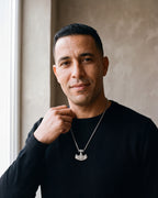 Man in a black merino crew-neck sweater by a window wearing the silver Atlas viking hammer pendant necklace