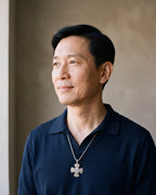 Man in a navy knit polo wearing the Atlas Viking knotwork cross pendant necklace in silver-tone steel