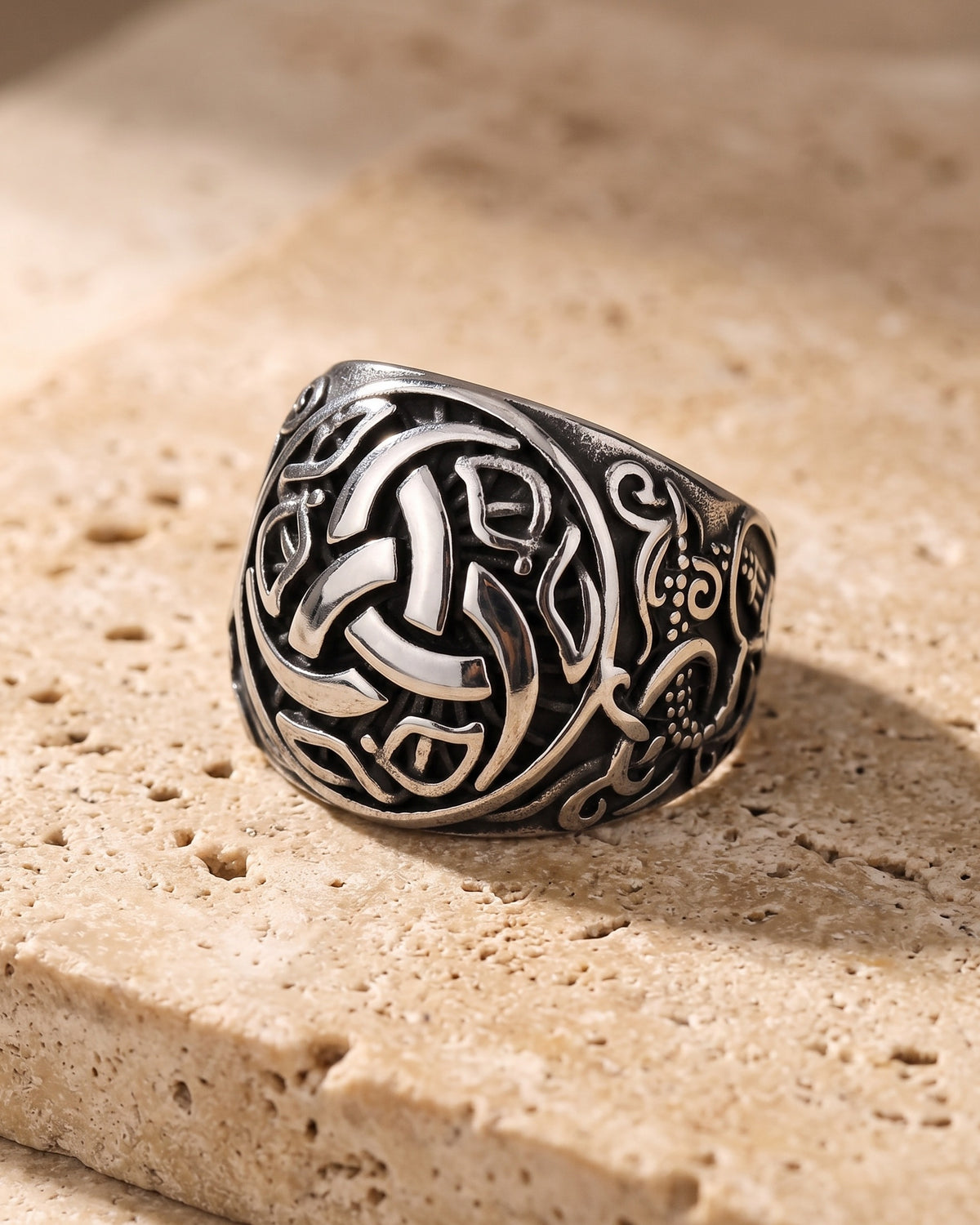 The whole antiqued silver-tone Atlas Viking knotwork ring laid on warm stone