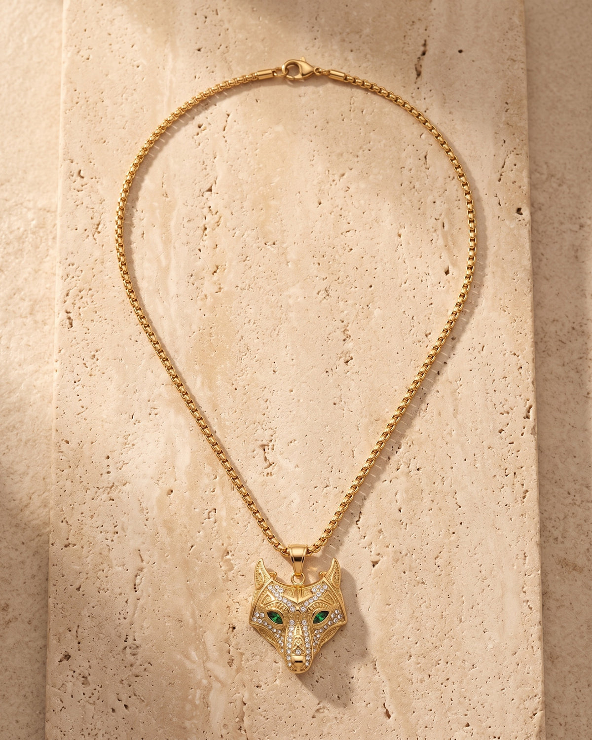 The whole gold-tone Atlas viking wolf pendant necklace lying on warm travertine stone