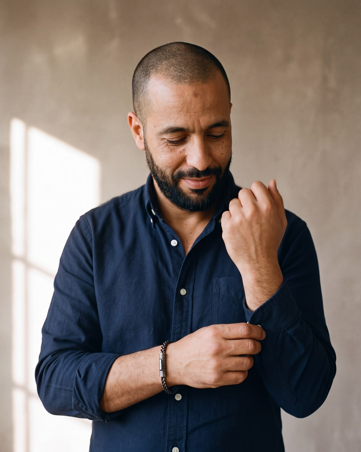 Man in a navy oxford shirt adjusting his sleeve wearing the antiqued black Atlas vintage wheat chain bracelet