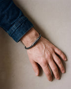 Close-up of the antiqued black Atlas vintage wheat chain bracelet worn by a man, shown at true size