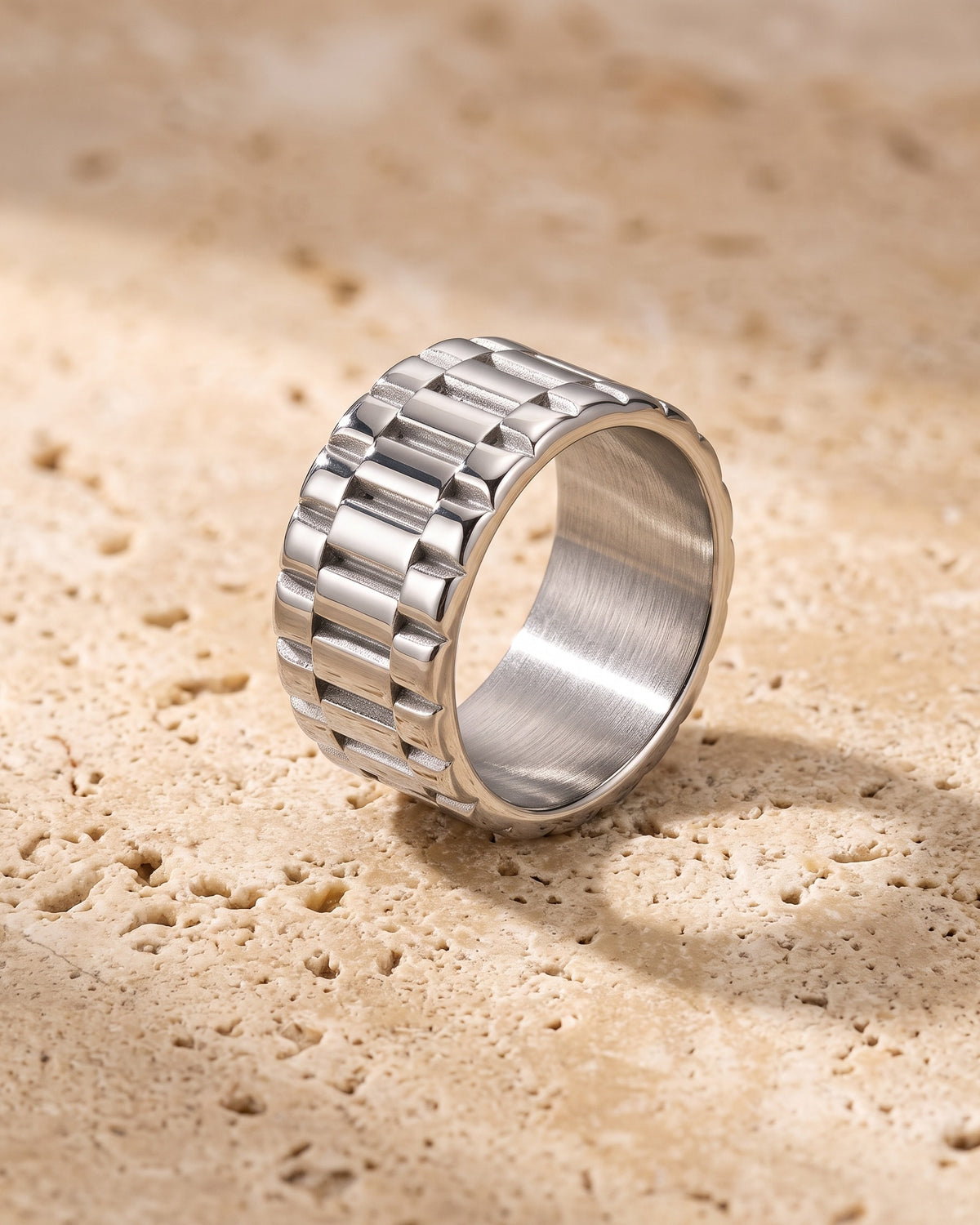 Entire Atlas watch link band ring in silver-tone steel, lying flat on warm stone