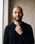 Man in a black merino sweater by a window wearing the Atlas watch link band ring in silver-tone steel