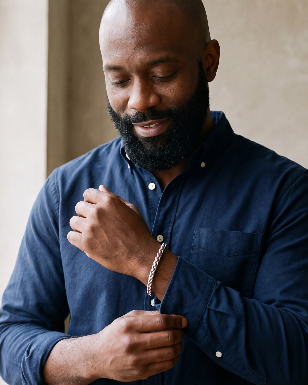Man in a navy shirt adjusting his sleeve, wearing the 6 mm Atlas wheat chain bracelet